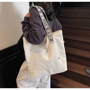 Close-up of ivory canvas tote bag with floral embroidered strap and metal ring detail