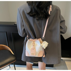 Detail view of pink and white geometric bucket bag with a cute plush pompom accessory