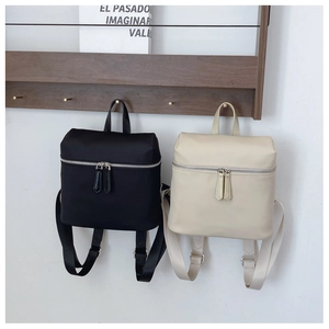 Detail of minimalist waterproof nylon backpacks in black and beige with dual zippers