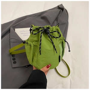 Detail of bright green drawstring bucket bag with mesh pocket and functional toggle
