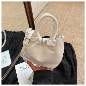 Detailed view of white pleated bucket bag with cloud-style design and silver hardware