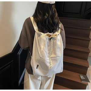 Detailed view of the large capacity checkered drawstring backpack worn on shoulders
