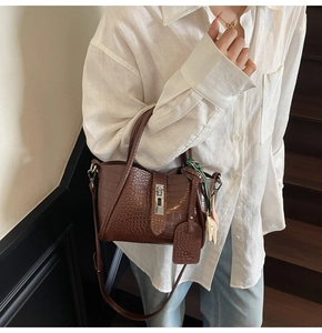 Detail of dark brown crocodile pattern leather handbag with silver metallic clasp closure