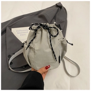 Close-up of light grey nylon drawstring bucket bag with mesh pocket and woven cord