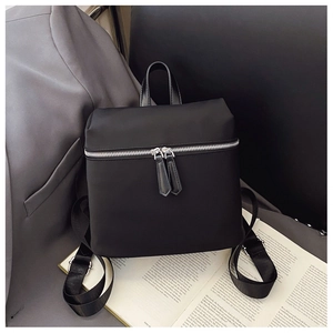 Detail of minimalist black backpack featuring durable nylon fabric and silver metal zippers