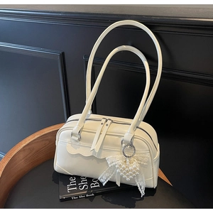 Close-up of cream PU leather pillow bag with pearl heart and lace bow charms