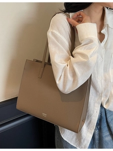 Minimalist large taupe tote bag in lychee pattern leather shown on model's shoulder