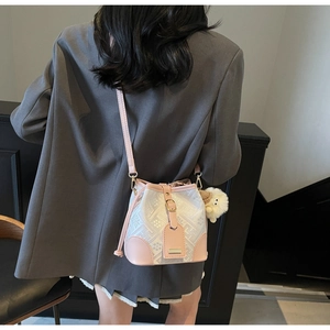 Detail showing pink and white patchwork bucket bag with crossbody strap and plush charm