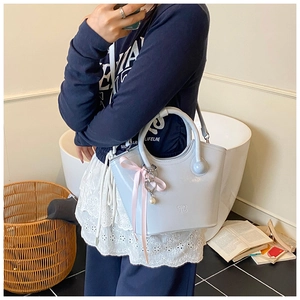 Détail d'un sac seau bleu clair avec nœud en soie et pendentif cœur en perle