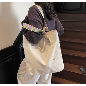 Detail of canvas tote bag with contrast yellow and purple strap on outdoor stairs