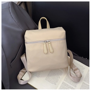 Detailed close-up of beige nylon backpack with dual zipper design and smooth texture