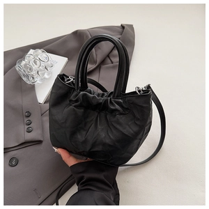 Detail of black pleated bucket bag featuring elegant leather texture and dual handles