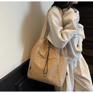 Detail of khaki drawstring tote bag with pleated nylon texture and side patterns