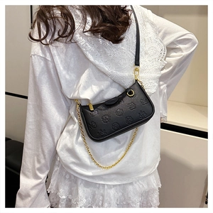 Detail of a black pebbled leather crossbody bag with embossed cartoon and gold chain