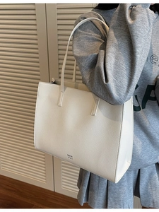 Minimalist beige large capacity tote bag in pebble leather worn by model over shoulder
