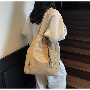 Detail of the woven brand tag and beige nylon texture on a large casual shoulder bag