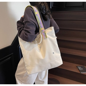 Detail of large canvas tote bag with a colorful striped woven shoulder strap