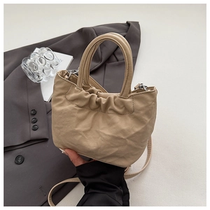 Detail of beige pleated bucket bag with round handles and detachable shoulder strap