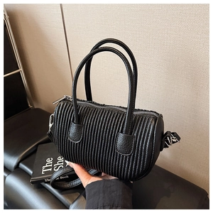 Detail of black pleated barrel bag featuring lychee texture leather and silver hardware