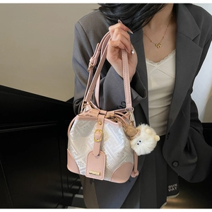 Crossbody bucket bag with pink leather trim and beige pattern texture on a female model