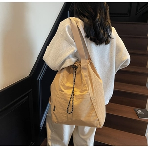 Detailed back view of a khaki drawstring tote bag with textured nylon on wooden stairs