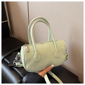 Macro detail of light green pleated crossbody bag with silver zipper and cylinder texture