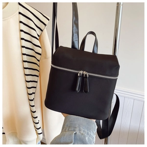 Close-up of black nylon backpack featuring silver metal zippers and minimalist design