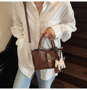 Detail of dark brown crocodile embossed leather mini tote with metal lock and silk scarf