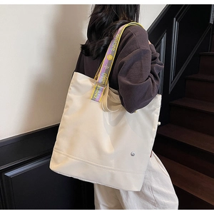 Detail of canvas tote bag with contrast yellow and purple straps on a model