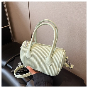 Detail of mint green barrel bag featuring vertical pleated texture and silver top zipper