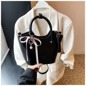 Détail d'un sac seau en cuir PU noir avec ruban rose et breloque cœur perlé