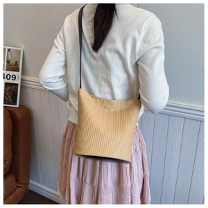 Detail of khaki woven bucket bag texture with black strap shown in home setting