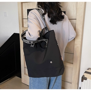 Detail of high-capacity black nylon tote bag with contrast jacquard logo shoulder strap