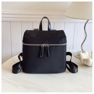Detail view of water-resistant black nylon backpack with silver zippers and top handle
