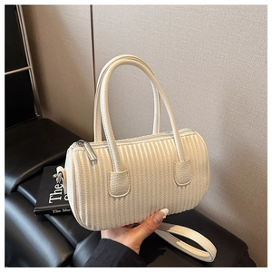 Detailed view of cream pleated barrel bag with silver hardware and detachable strap