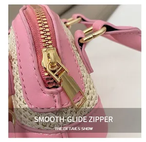 Detailaufnahme des glatten goldenen Reißverschlusses an der rosa Leder-Strohtasche