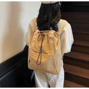 Detail of beige nylon drawstring backpack with bicolored cord on a person's back