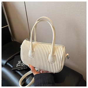 Close-up of beige cylindrical handbag with vertical pleats and lychee texture leather