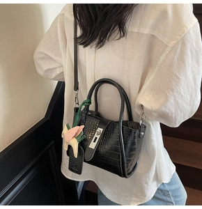 Detail of black crocodile texture bucket bag with silver lock and a pony charm on stairs