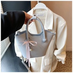 Détail d'un sac seau bleu clair avec un nœud en ruban rose et un pendentif en perles