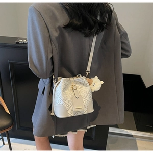 Detail view of cream bucket bag showing intricate floral jacquard fabric and plush sheep charm