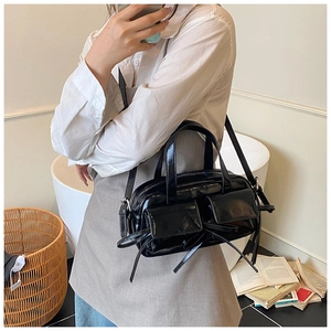 Détail du sac bowling en cuir verni noir avec poches cargo et bandoulière réglable