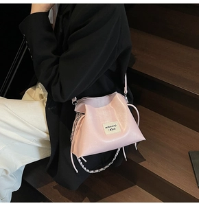 Detail of pink bucket bag with branded label and silver chain strap on model