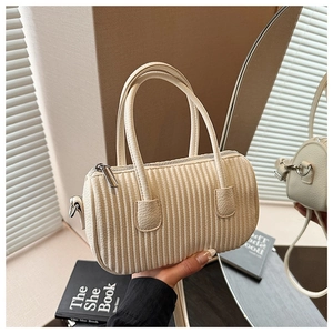 Detail of cream pleated cylindrical boston bag showing textured leather and metal zipper