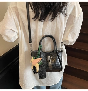 Black crocodile embossed bucket bag with horse charm detail shown on model over shoulder