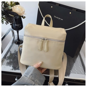 Detail view of the beige mini backpack featuring smooth faux leather and dual zip closures