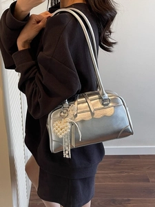 Metallic silver Boston bag with scalloped edges and pearl pendant on a model's shoulder