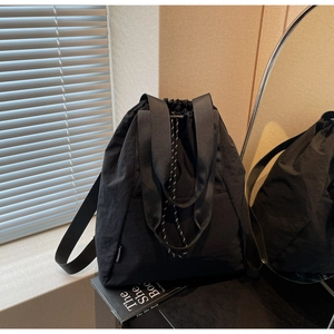 Close-up of black nylon drawstring backpack showing the side brand label and texture