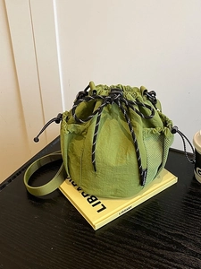 Green nylon drawstring bucket bag with mesh side pockets and woven shoulder strap