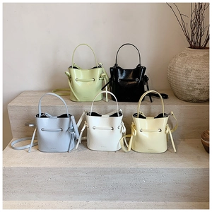 Mini bucket bags in five colors displayed on textured steps with elegant ceramic decor